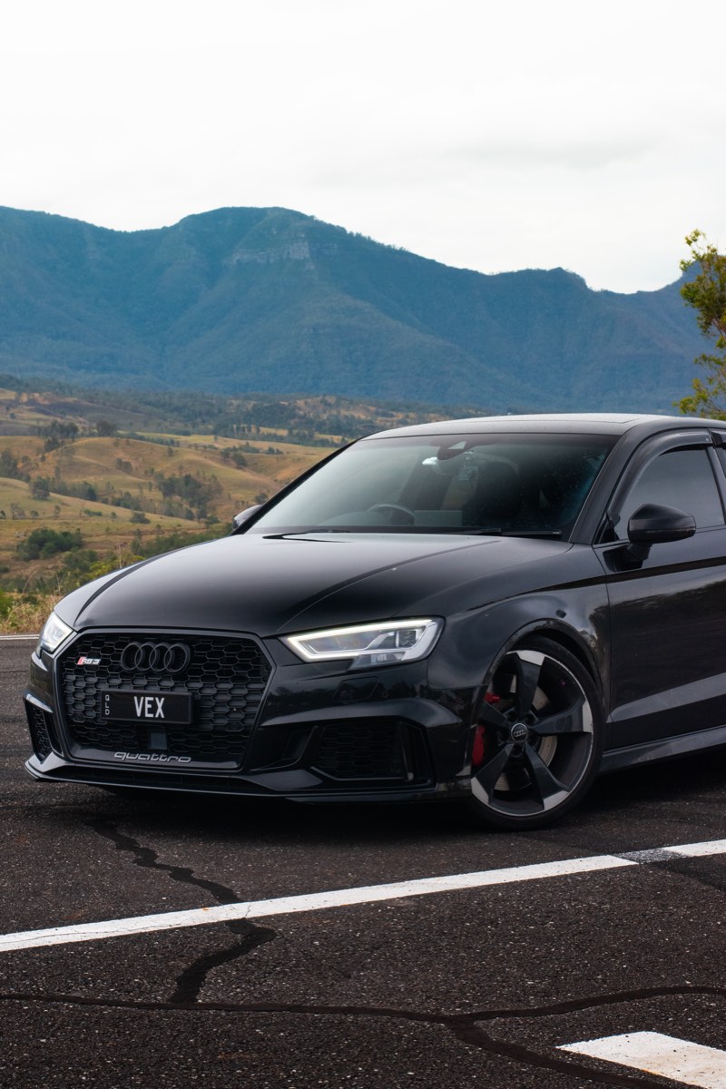 Front-quarter view of an Audi RS3 on a mountain helipad under grey skies