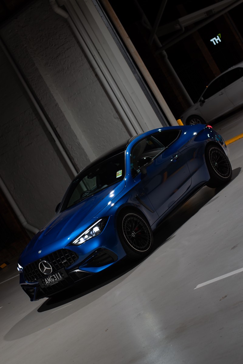 Angled night photograph of the Mercedes-AMG CLE53 coupe in an industrial setting